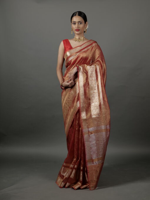 "Model wearing a stunning orange crushed tissue silk saree with elegant gold zari accents." By Mirra Clothing