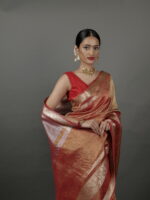 "Close-up of an orange crushed tissue silk saree, showcasing shimmering gold zari patterns."By Mirra Clothing