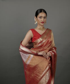 "Close-up of an orange crushed tissue silk saree, showcasing shimmering gold zari patterns."By Mirra Clothing