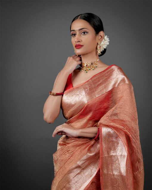 "Close-up of an orange crushed tissue silk saree, highlighting its unique crinkle effect."By Mirra Clothing